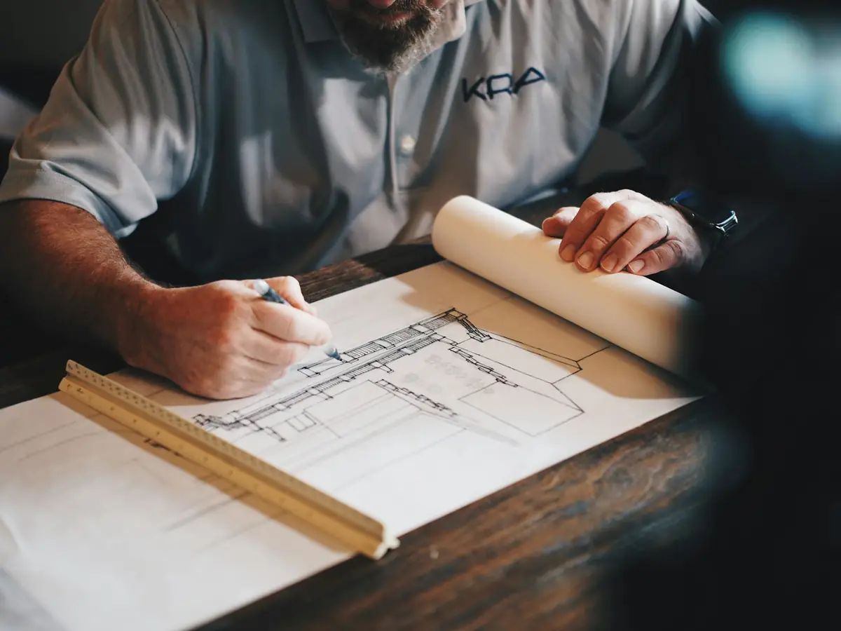 Mains travaillant sur un plan, crayon et règle