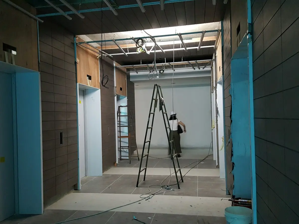 Plaquiste sur un escabeau dans des locaux en cours de cloisonnement